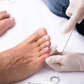 Someone filing toe nails while wearing gloves.