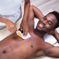 Man getting his chest waxed with his arms behind his head.