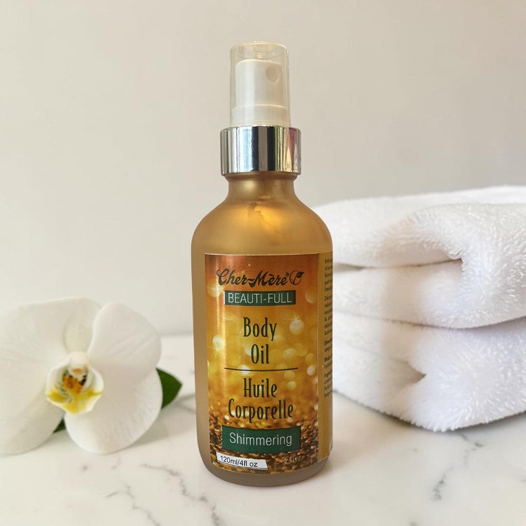 Bottle of Cher Meri Body Oil with a white orchid and towel on a marble surface
