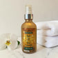 Bottle of Cher Meri Body Oil with a white orchid and towel on a marble surface